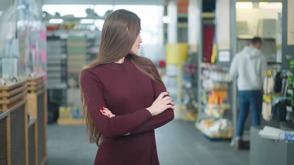 Portrait of Annoyed Young Caucasian Woman Standing in Building Store Looking Back at Man Choosing