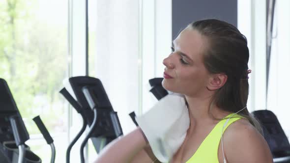 Beautiful Woman Wiping Her Neck with a Towel After Workout at the Gym