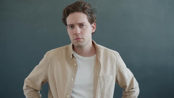 Portrait of Unhappy Man Looking at Camera with Worried Facial Expression Standing on Gray Background
