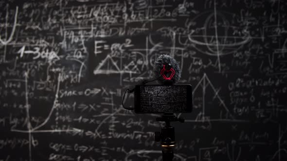 Smartphone with Microphone Standing on Tripod and Recording Blackboard with Different Formulas