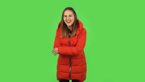 Lovely Girl in a Red Down Jacket Is Laughing. Green Screen