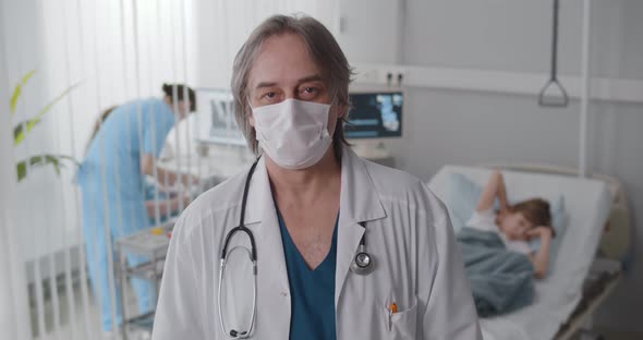 Doctor Wearing Protective Mask Posing at Camera in Pediatrics Ward