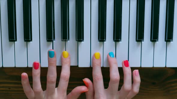 A Young Positive Girl with Beautiful Hands and a Color Manicure Plays Piano.