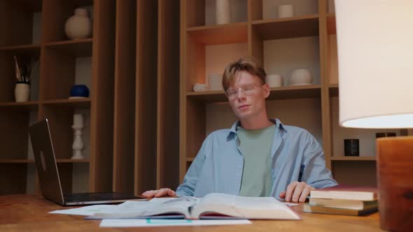 Young Man in Glasses Studying and Stressing to Learn Somethingin Warm Wood Room