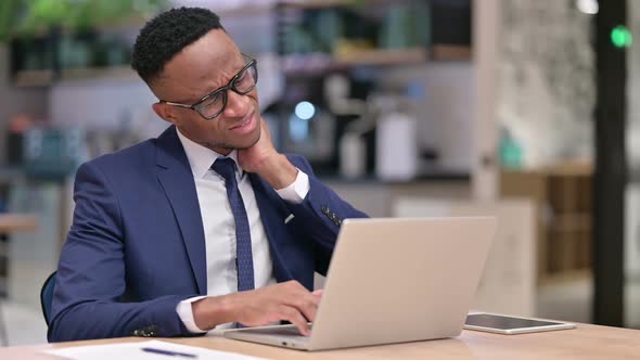 Tired African Businessman with Laptop Having Neck Pain in Office