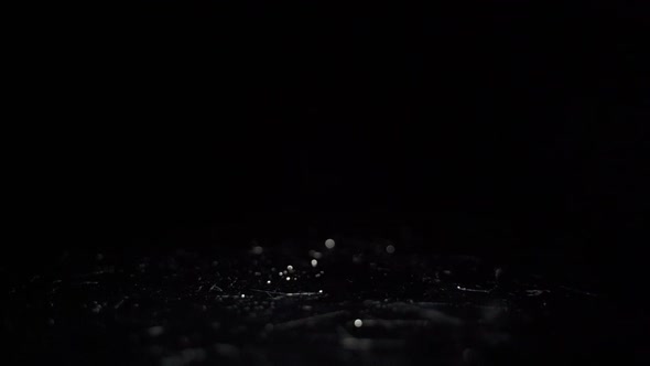 Water drops falling in black low light in slow motion close-up