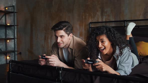 Excited Lady and Fellow in Casual Outfit are Laughing Holding Wireless Joysticks and Playing Video