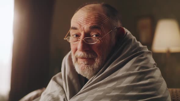 Senior Man in Glasses Wrapped in Blanket