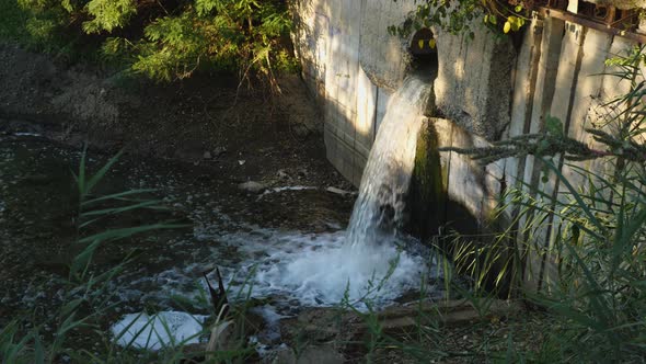 Sewage water falls into the river from the concrete wall