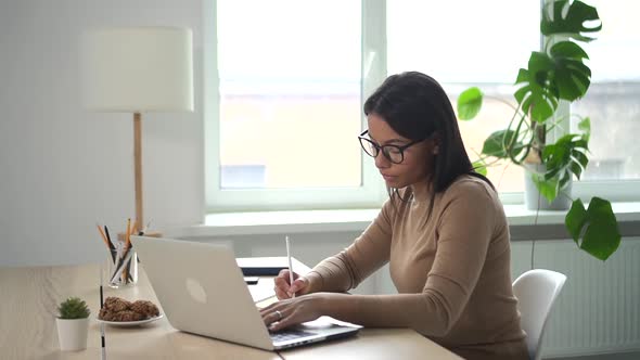 Beautiful African Woman Writes Data From Computer in Notebook at Table Spbd