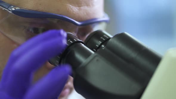 Face View of Man Looking Through Eyepiece of Microscope in Work Process in Pharmaceutical Lab Spbd alt