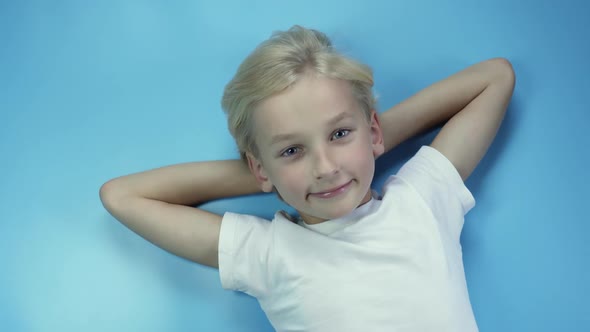 Portrait of a Lying Eightyearold Boy on a Blue Background alt