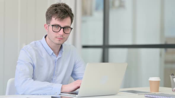 Young Man with Laptop Smiling at Camera