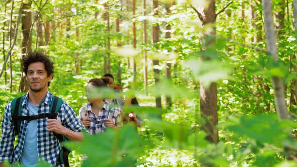 Group of Friends with Backpacks Hiking in Forest