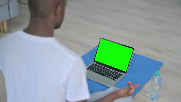 Rear View of African Man Doing Yoga While Looking at Laptop with Chroma Key Screen