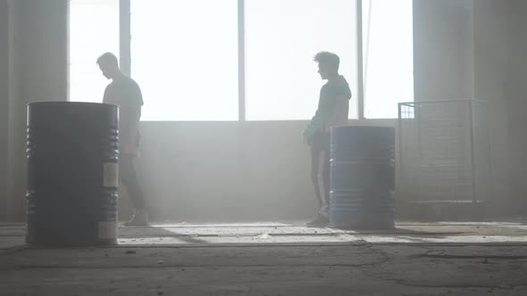 Two Young Men Practicing Dancing Breakdance in the Dusty Room of Abandoned Building