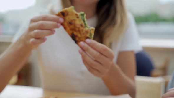 A Woman Eats Pizza in a Street Cafe