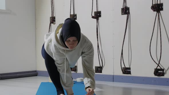 A Young Woman in Hijab Warms Up Her Body