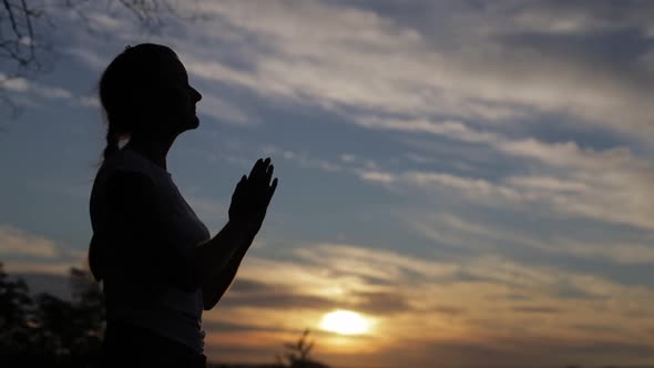 Silhouette of a woman praying with Amazing dramatic sky sunset background.