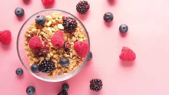 Granola and Berries in Bowl on Pink Background