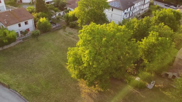 Drone view of a field near houses during a sunset in Italy, nice sun rays.