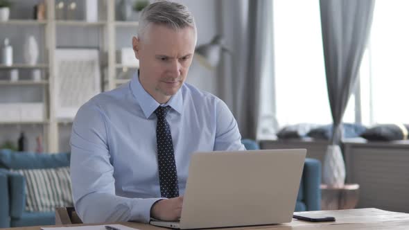 Pensive Gray Hair Businessman Working on Laptop