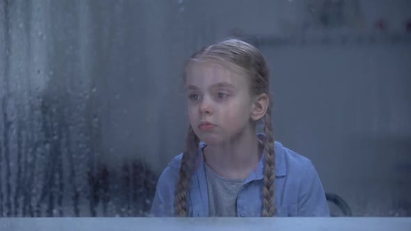 Lonely Girl Looking at Window in Rainy Weather, Waiting Parents From Work