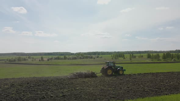 Tractor plows the land on a green uncultivated field