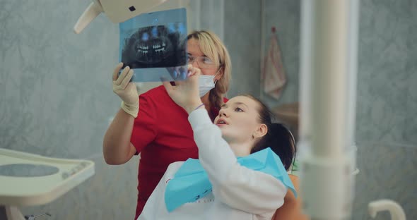 Dentist Carefully Looks at the Xray Picture with the Patient and Decides Which Teeth Should Be
