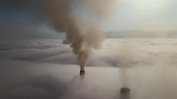 Coal Power Plant High Pipes with Black Smoke Moving Upwards Over Clouds Polluting Atmosphere