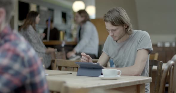 Man using digital tablet while sitting in pub