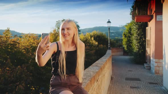 Pretty Woman Making Selfie on Smartphone in Front of Beautiful Nature Landscape