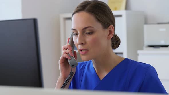 Doctor with Computer Calling on Phone at Hospital