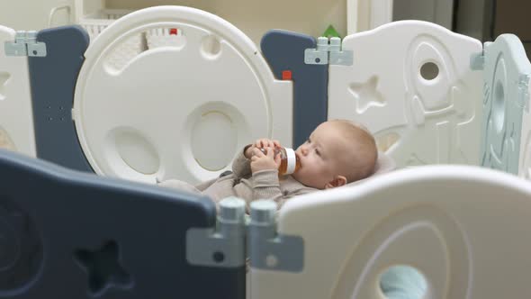 Baby Drinks Juice From His Bottle 8 Month Old Caucasian Toddler Sits in a Rocking Chair for Babies