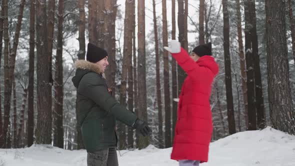 Young Man Embracing Woman Outdoors in Winter Forest