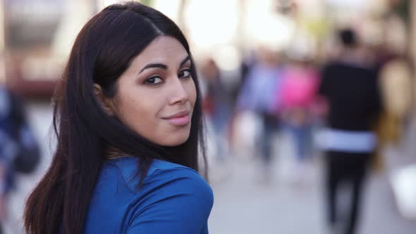 Beautiful young asian woman in the street turning her head and smiling at camera