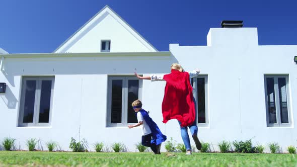 Mother and son in superhero costume having fun in garden 4k