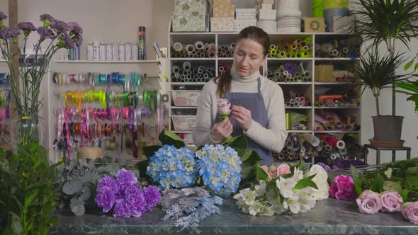 Cute Mature Woman Florist Collects a Bouquet and Looks at the Flowers with Tenderness