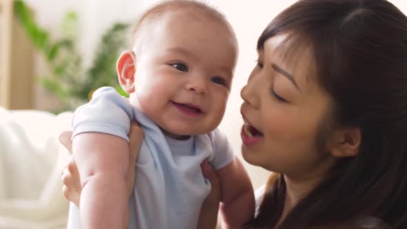 Happy Young Mother Kissing Little Baby at Home