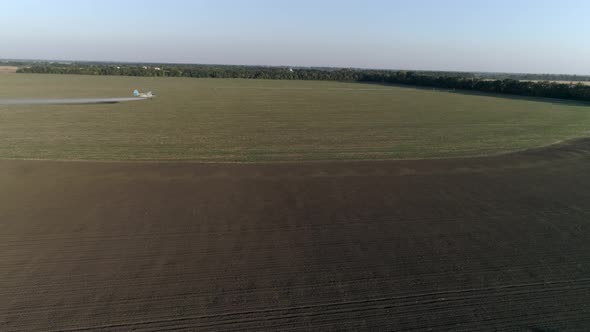 Crop Duster Flies Over Field with Wheat and Splashing Chemicals Against Parasite in Drone View of