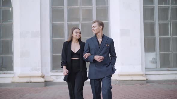 Portrait of Positive Young Caucasian Couple Walking and Talking in Urban City