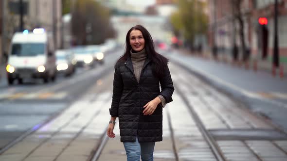 Adult Woman Is Walking in City at Autumn, Strolling on Center of Tram Lines