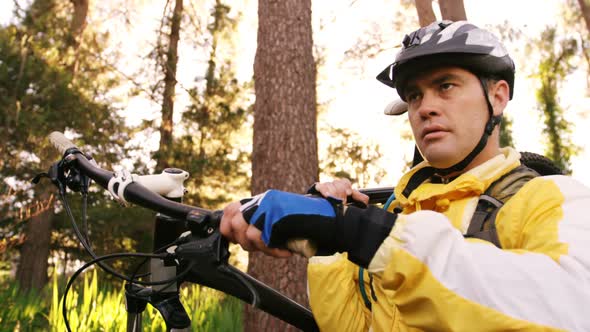 Male mountain biker carrying bicycle in the forest