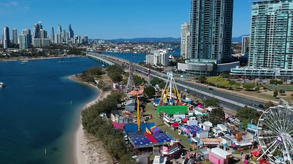 Aerial view of a colourful carnival situated by the sea with a city skyline in the background