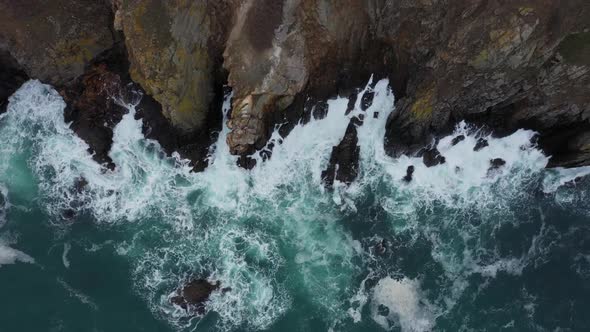 Aerial view of ocean waves splashing in the rocky beach