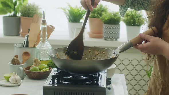 Woman stirring ingredients in frying pan