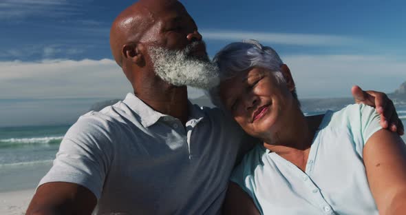 Happy senior african american couple sitting and embracing at the beach