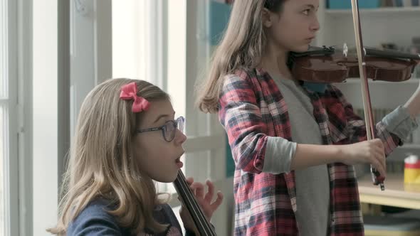 Girls playing violin and cello during lesson