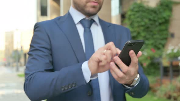 Hands Close up of Businessman using Smartphone while Walking in Street