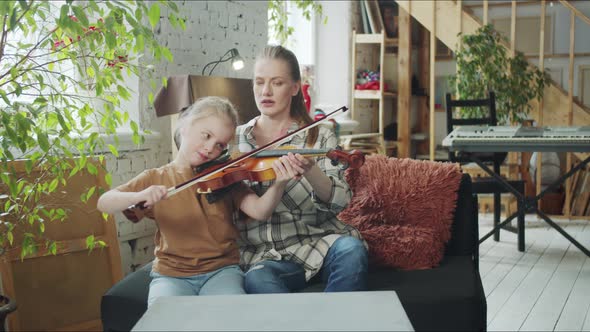 The Tutor Helps the Girl to Play the Violin and Adjusts the Bow